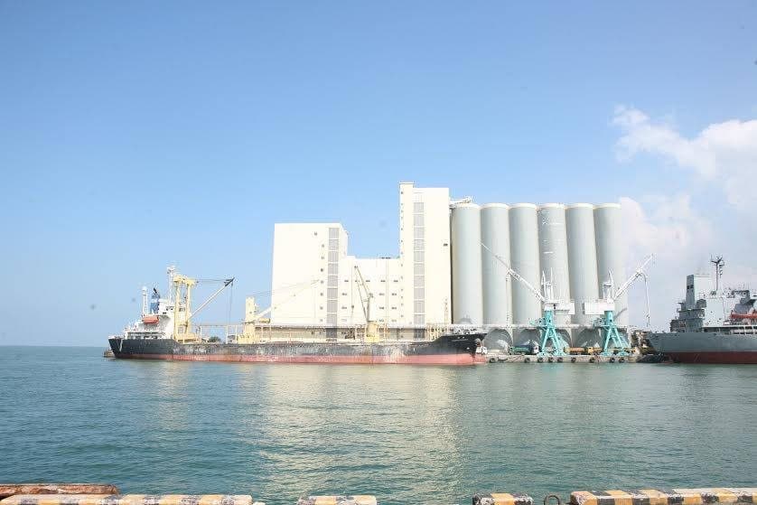 Bulk storage silos and loading facilities at a port with vessels berthed alongside